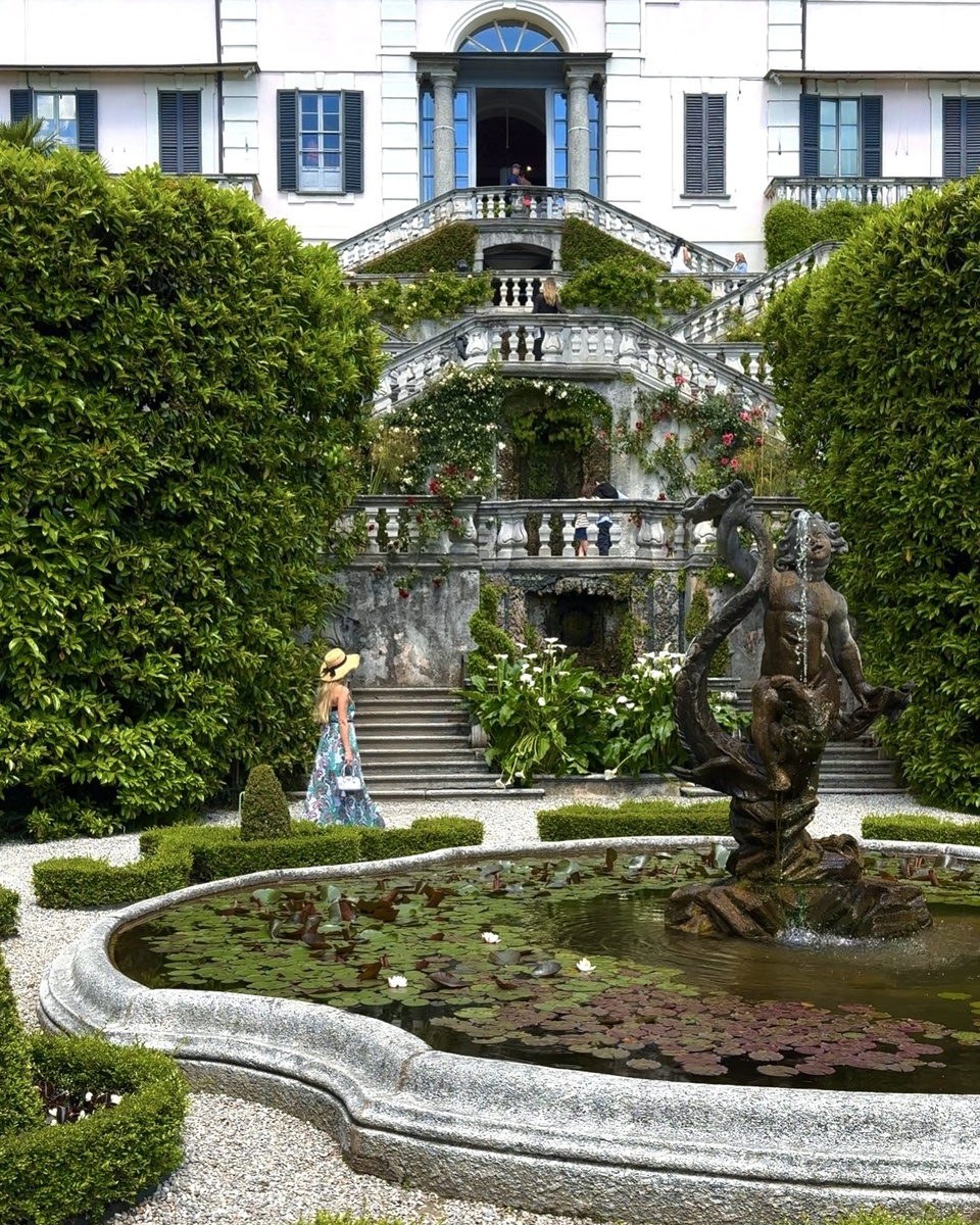 Villa Carlotta's stone staircase rises behind a fountain and water-lily pond framed by clipped hedges.
