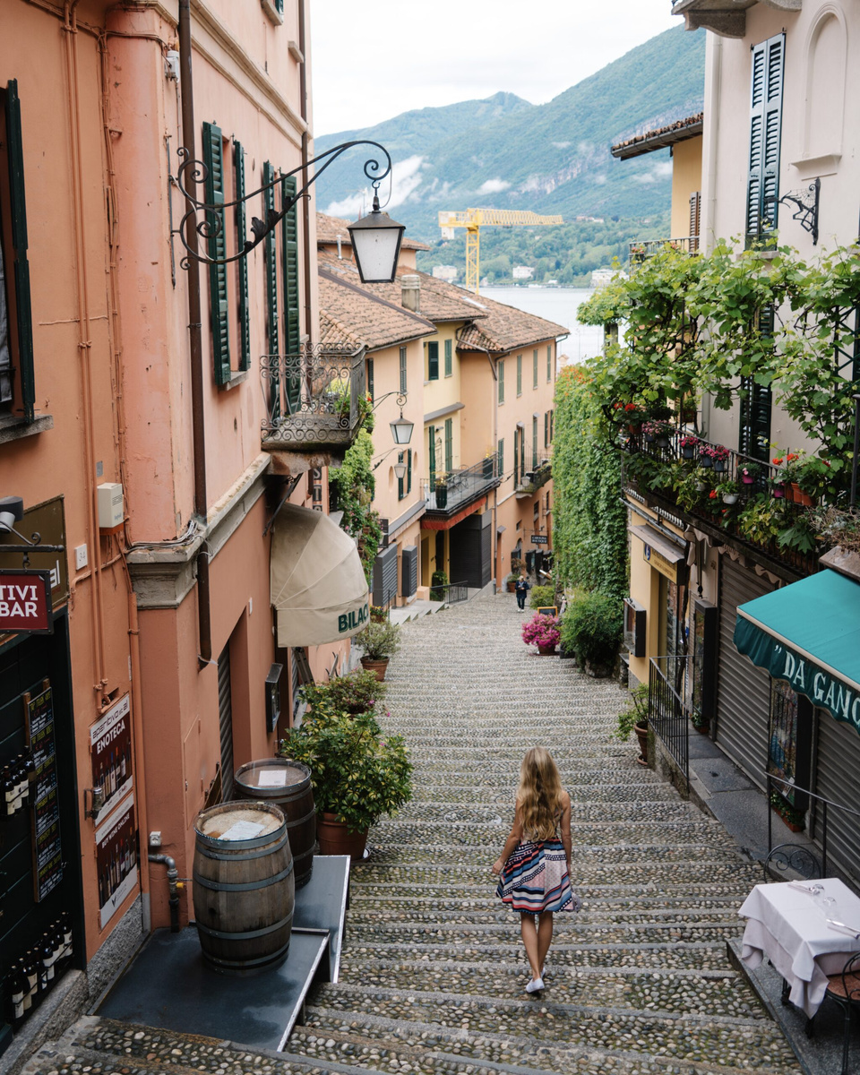 Olga walks down a cobbled staircase between pastel buildings in Bellagio.
