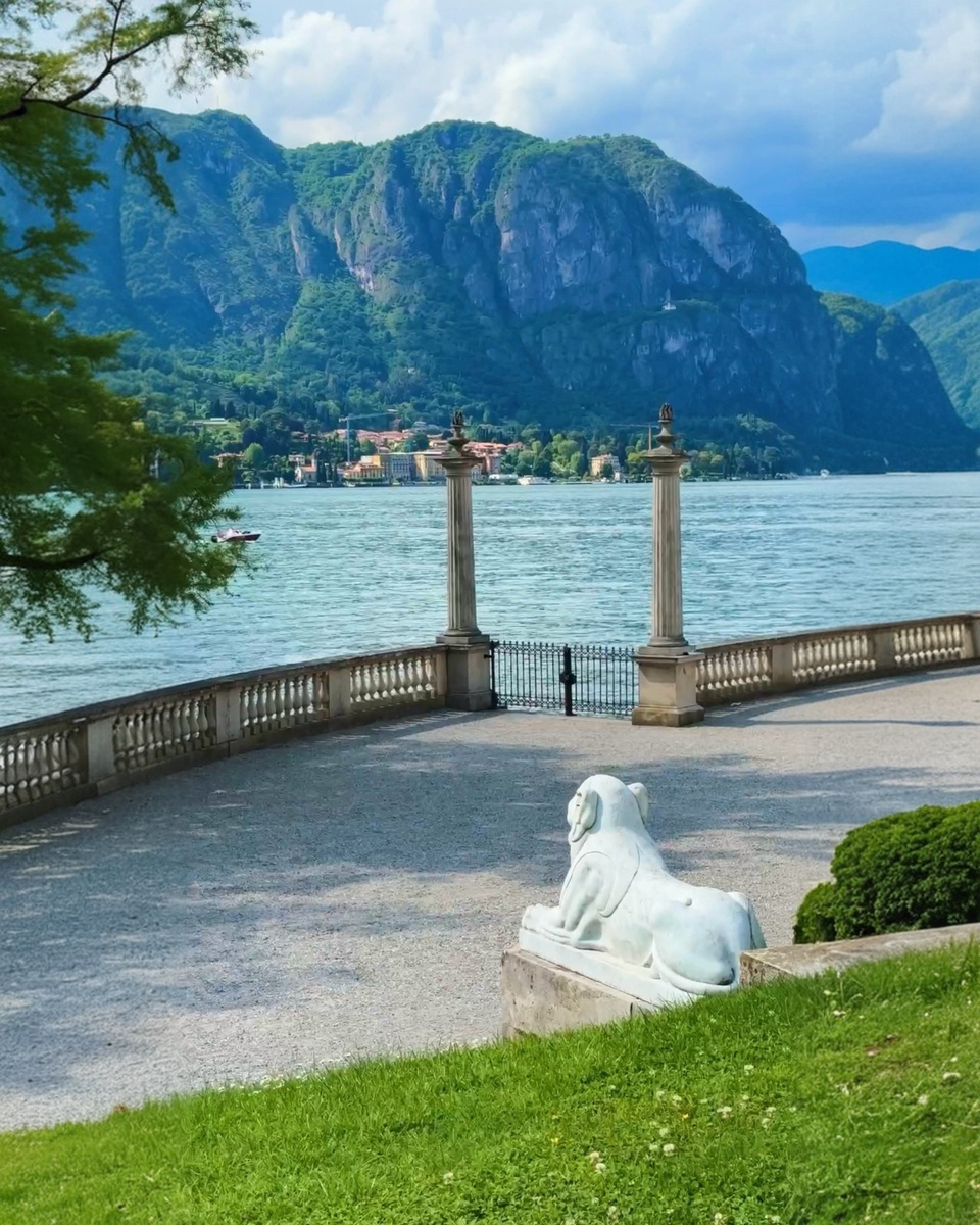 A stone sphinx and balustrade overlook Lake Como in the gardens of Villa Melzi.
