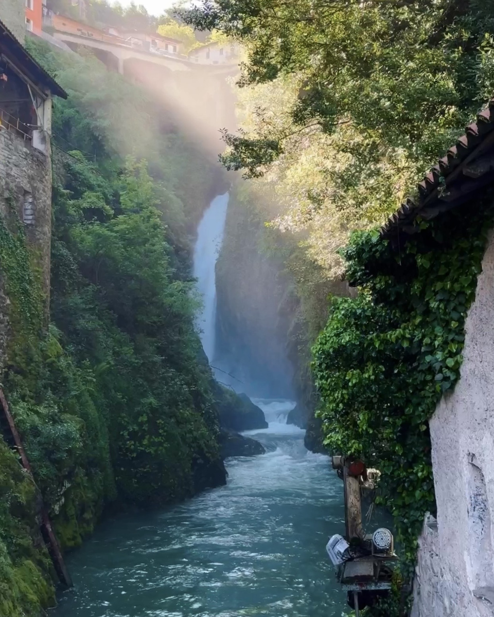 A waterfall plunges through the narrow, wooded gorge of Orrido di Nesso.