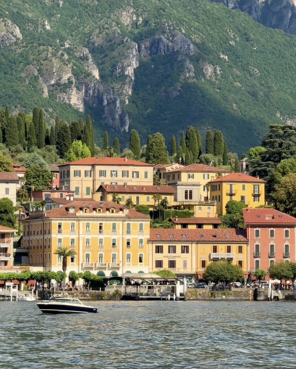 Colorful waterfront buildings and steep green mountains seen from a boat on Lake Como.