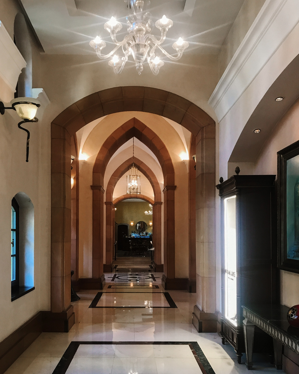 A bright corridor at Four Seasons Sultanahmet with repeated pointed arches, chandeliers and a marble floor.