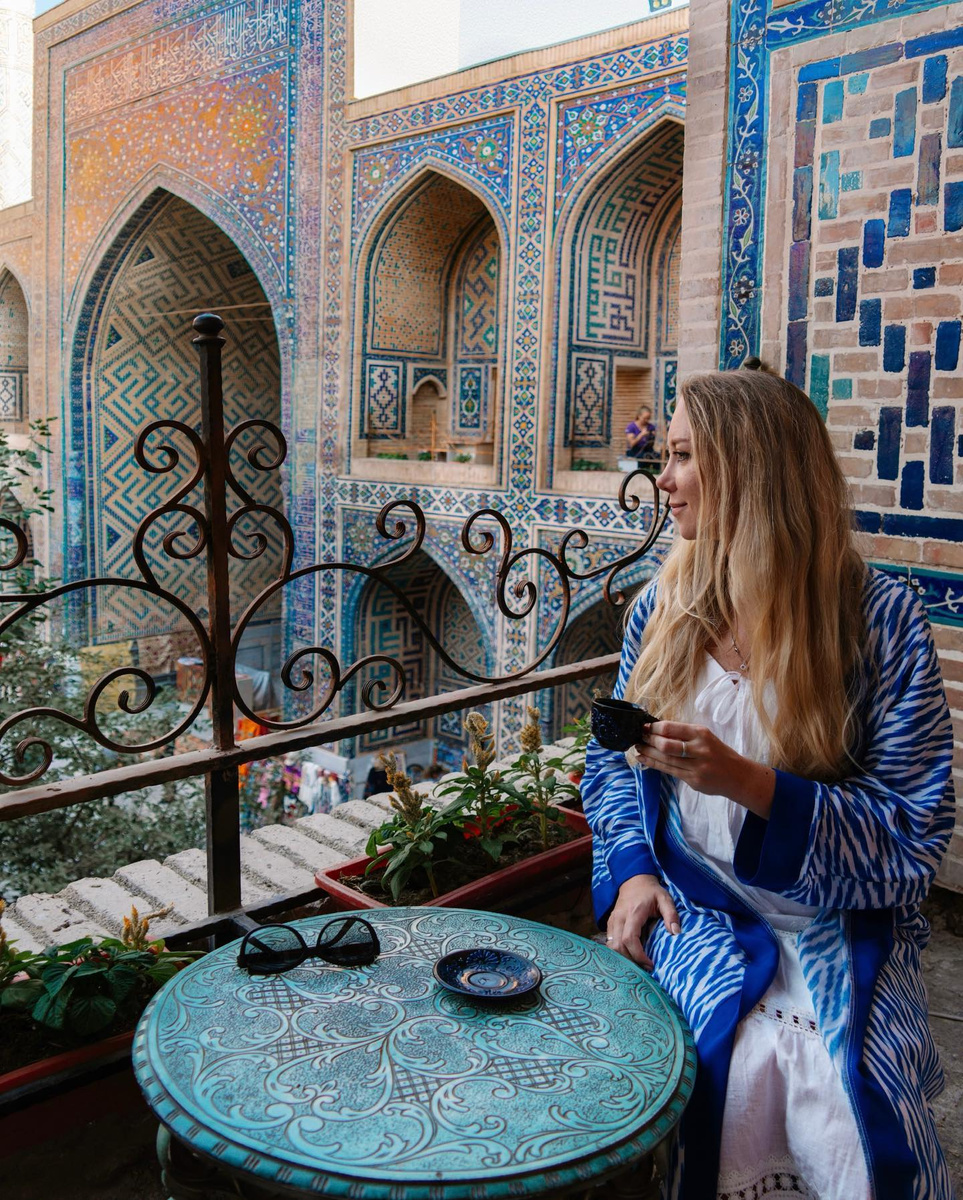 Olga at a table framed by intricate blue tilework in Uzbekistan.