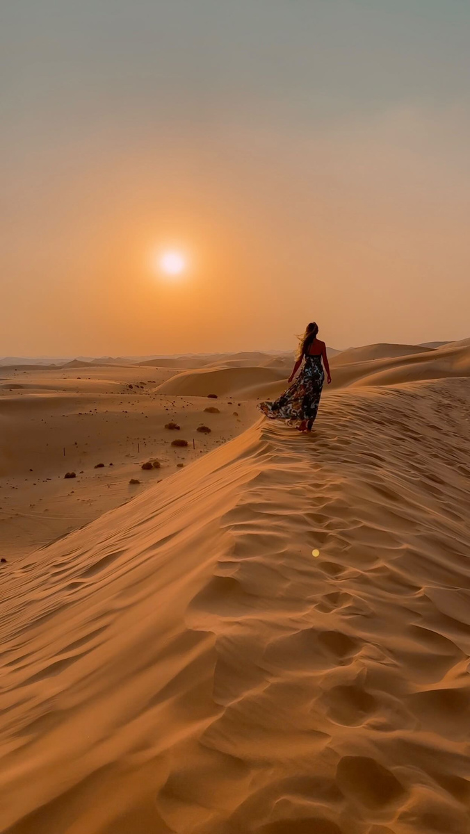 Olga seated on a desert dune at sunset in the United Arab Emirates.
