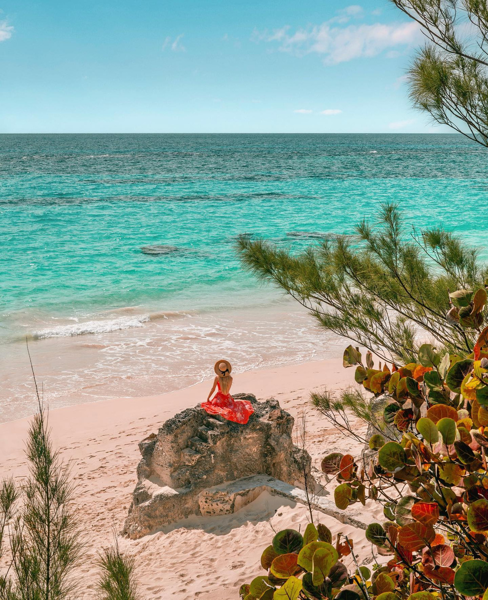 Olga seated above a rocky cove and clear blue water in Bermuda.