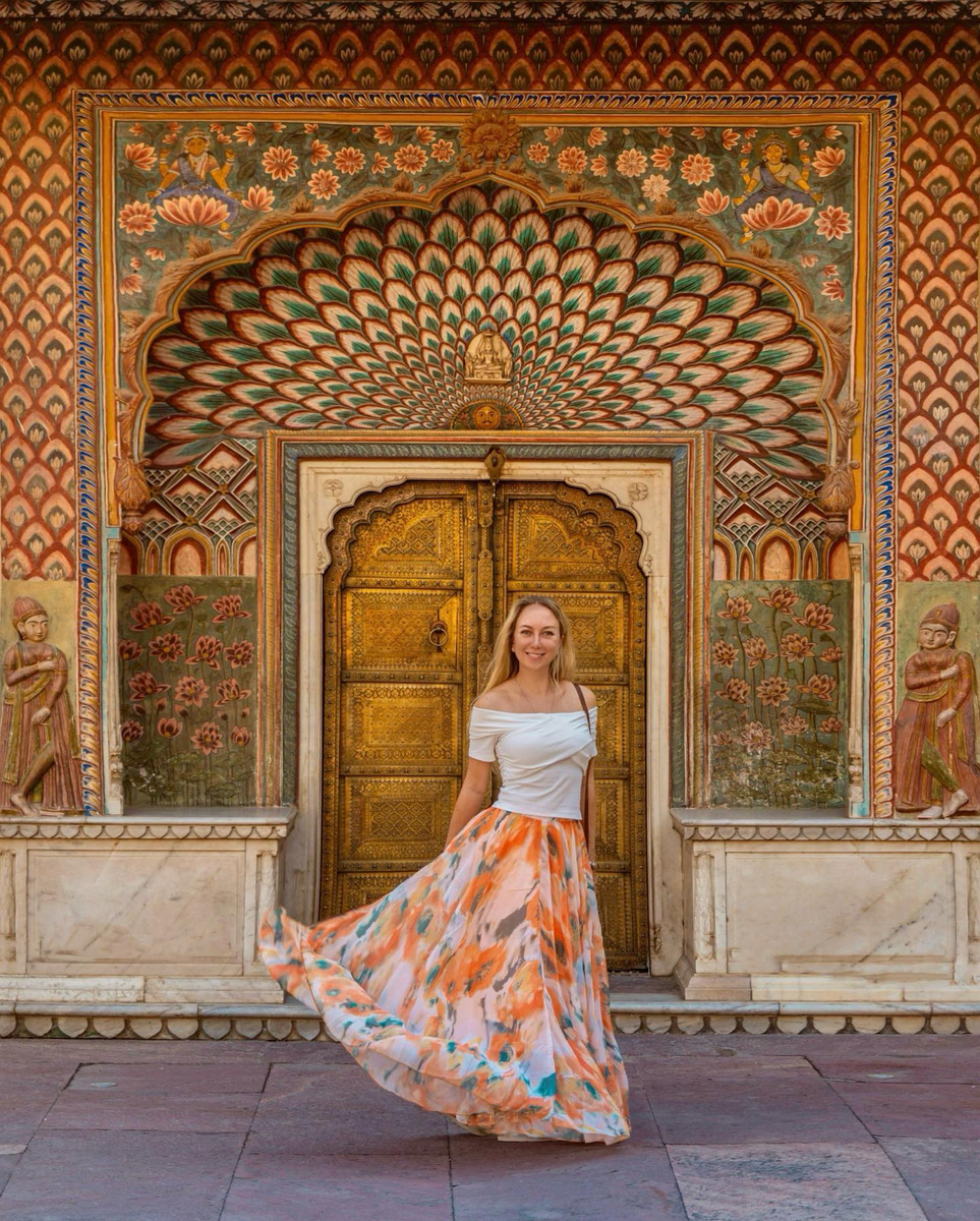 Olga seated before an ornate painted doorway in Jaipur.