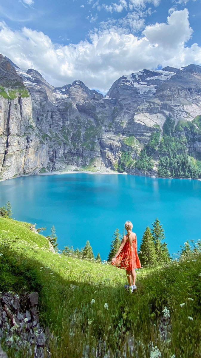 Olga in a red dress above the turquoise water of Oeschinensee.