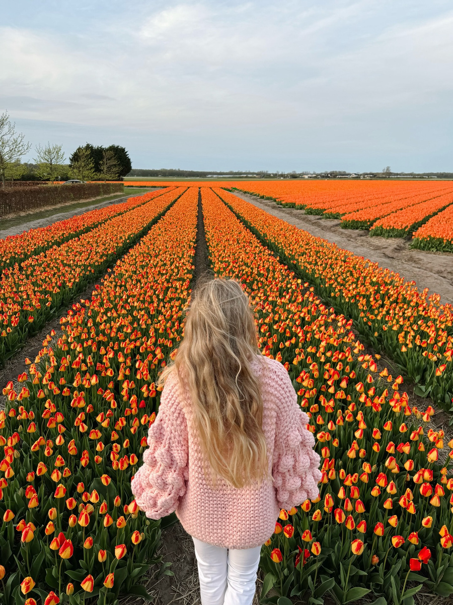 Olga standing before a broad field of tulips in the Netherlands.