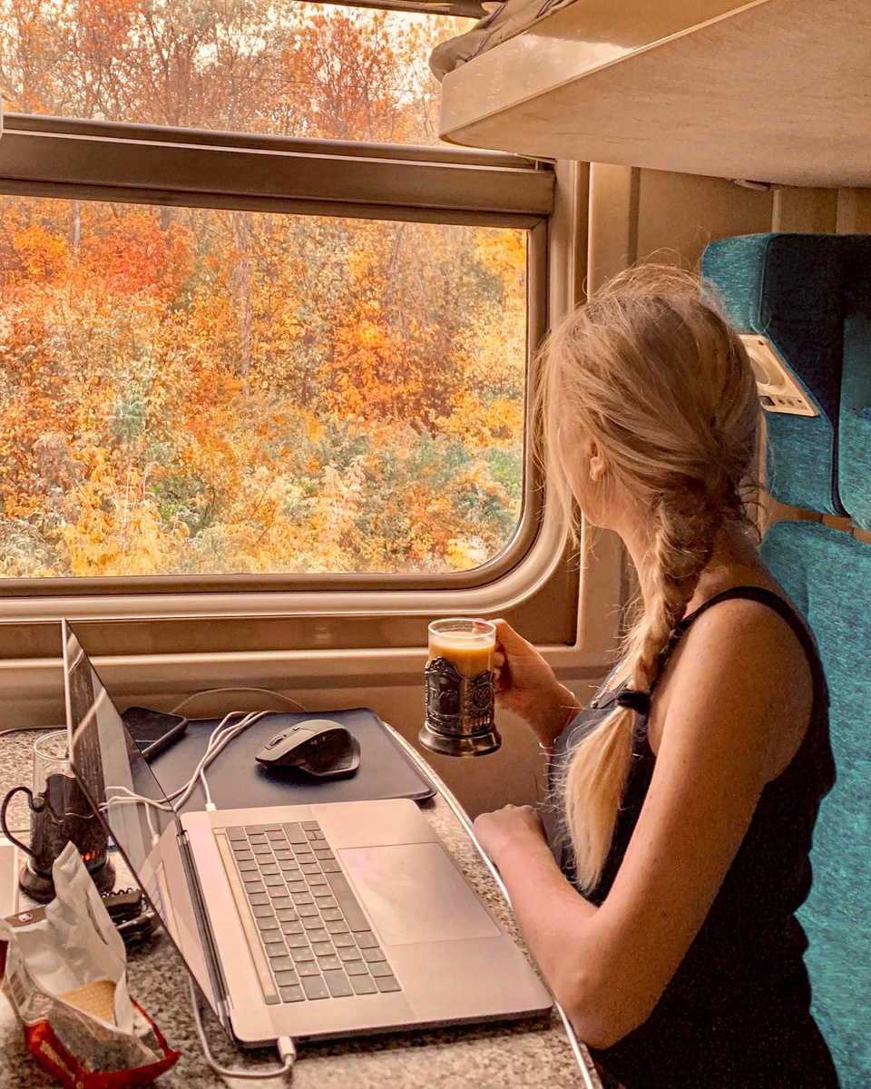 Olga watching autumn forest pass the window of a train crossing Russia.