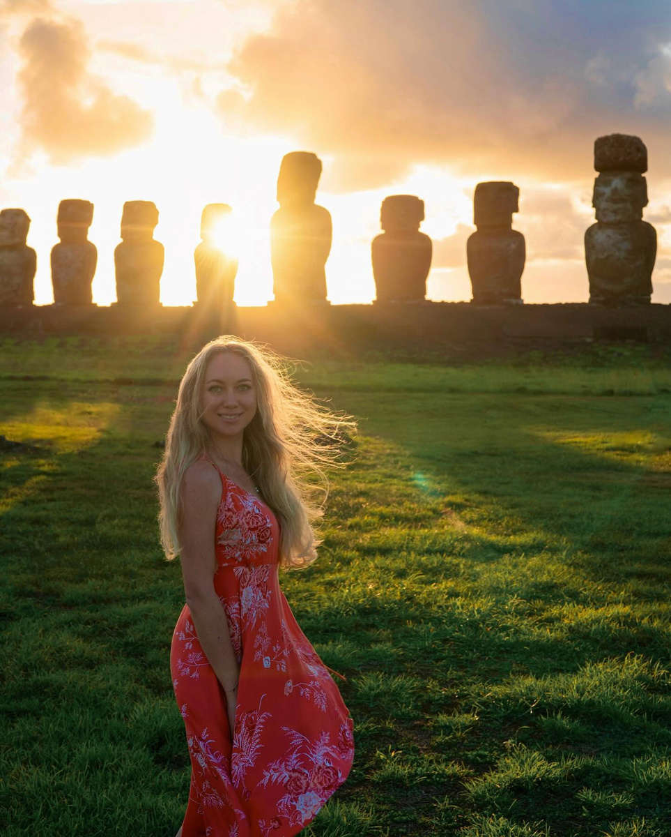 Olga in a red dress before the moai of Ahu Tongariki at sunrise.