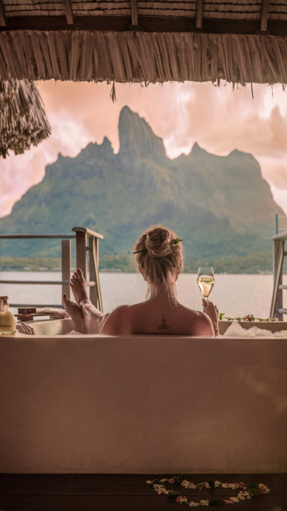 Olga in a freestanding bath facing Mount Otemanu through open doors at Four Seasons Bora Bora