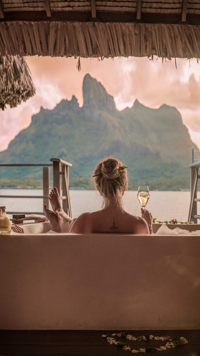 Olga in a freestanding bath facing Mount Otemanu through open doors at Four Seasons Bora Bora