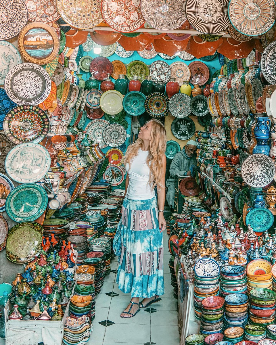 Olga surrounded by patterned ceramic bowls in a Marrakech souk.