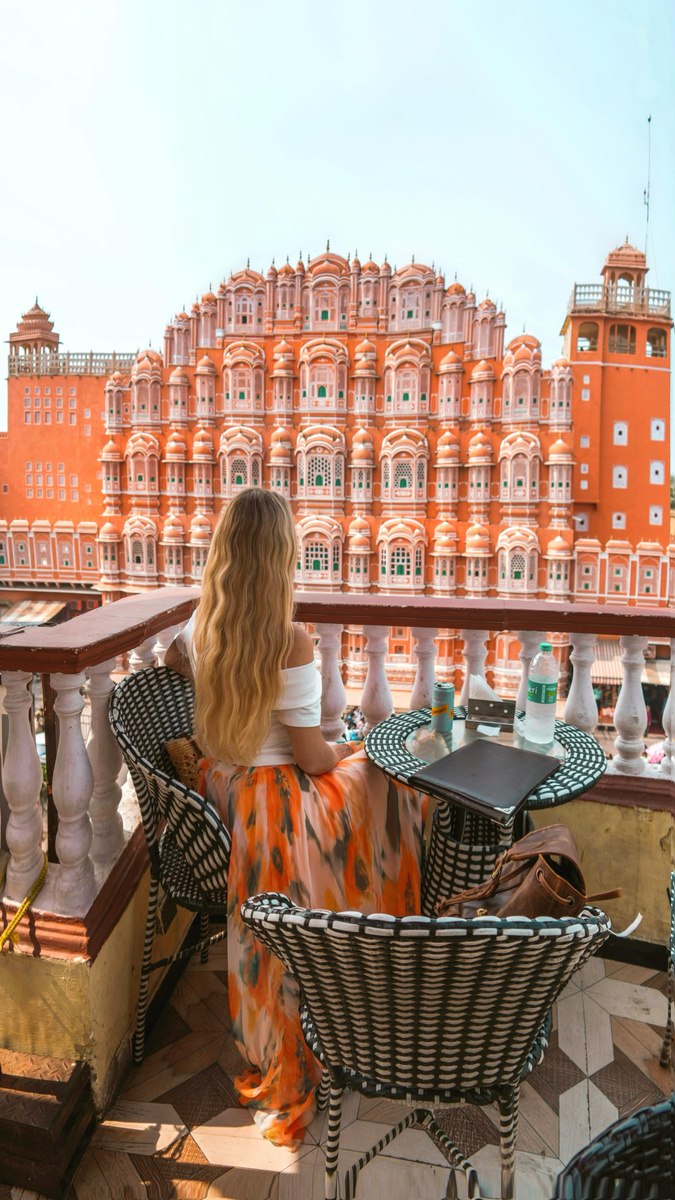 Olga looking across a terrace towards the pink façade of Hawa Mahal in Jaipur.