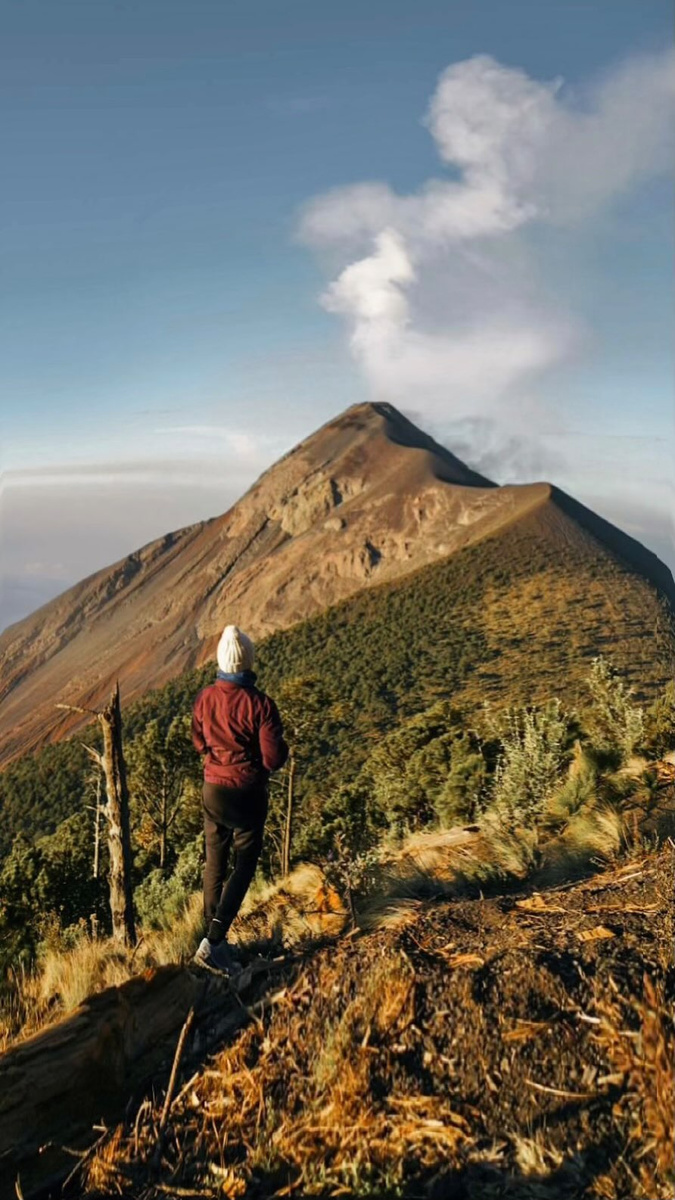 A hiker facing the volcanic peaks on an Acatenango trek in Guatemala.
