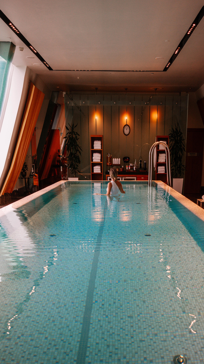 Olga stands in the indoor pool at Four Seasons Gresham Palace Budapest beneath sloping glass windows.