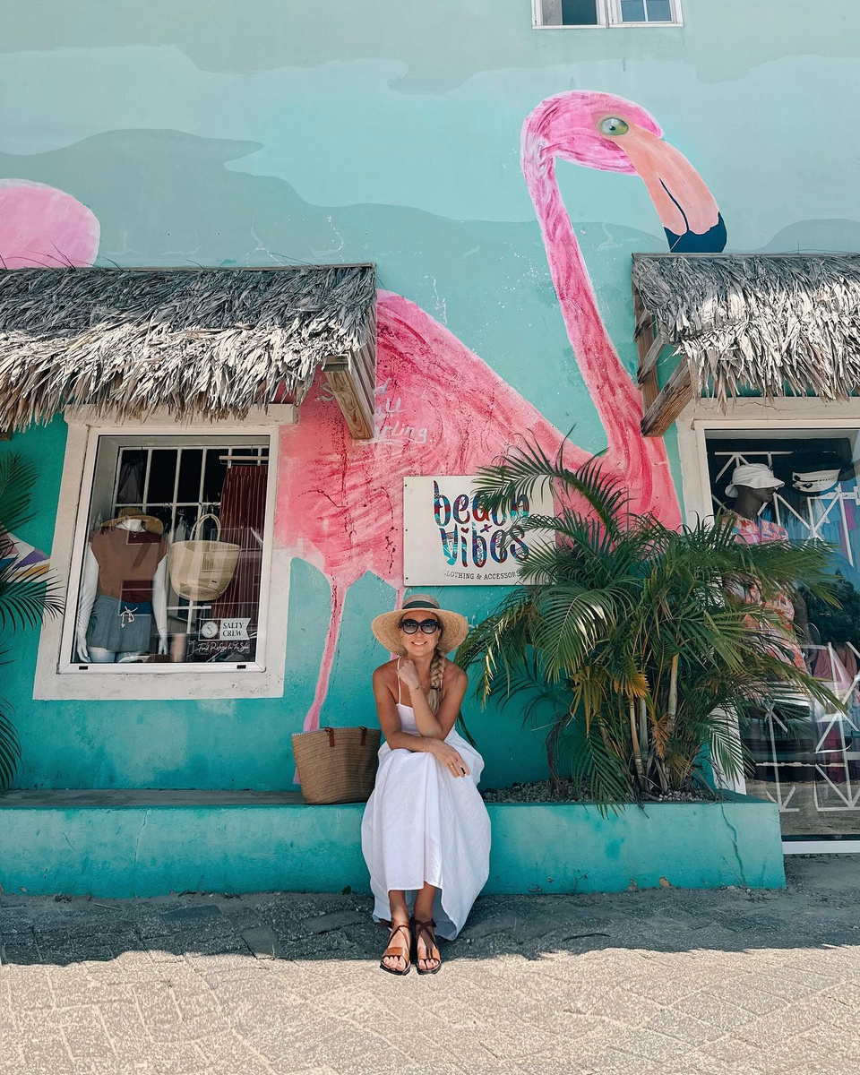 Olga standing before a bright pink flamingo mural in Bonaire.