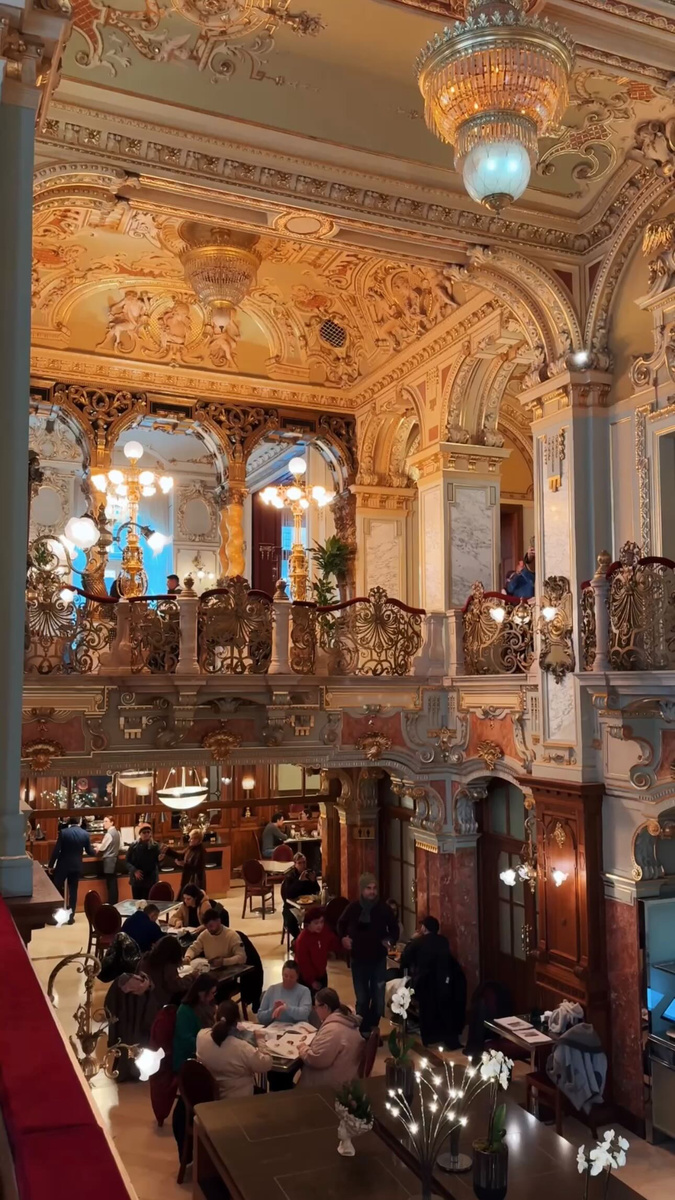 The ornate gilded interior of New York Café in Budapest, seen from an upper gallery.