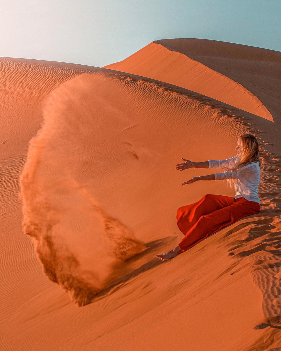 Olga sending a sweep of orange sand down a tall Sahara dune.