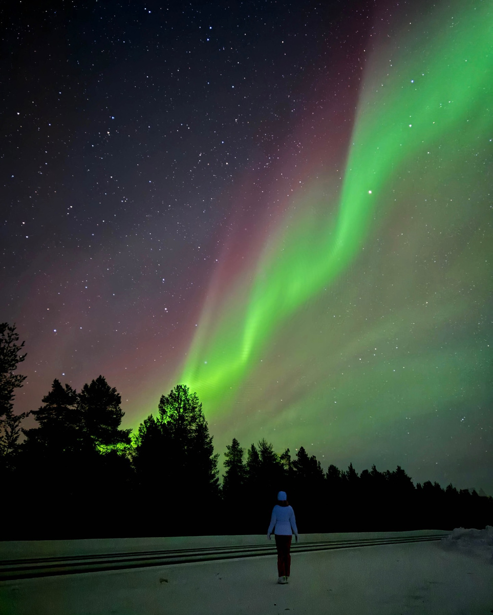 The northern lights arching above Olga in snowy Finnish Lapland.