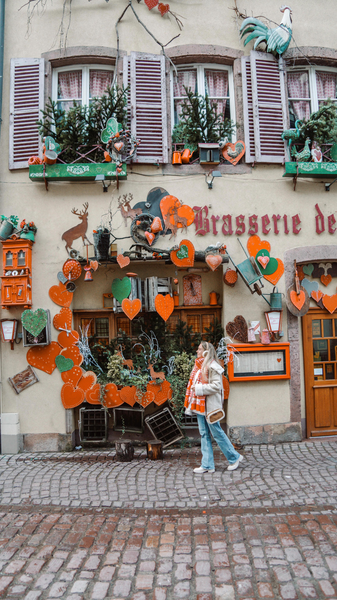 Olga outside a richly decorated Christmas shopfront in an Alsatian village.