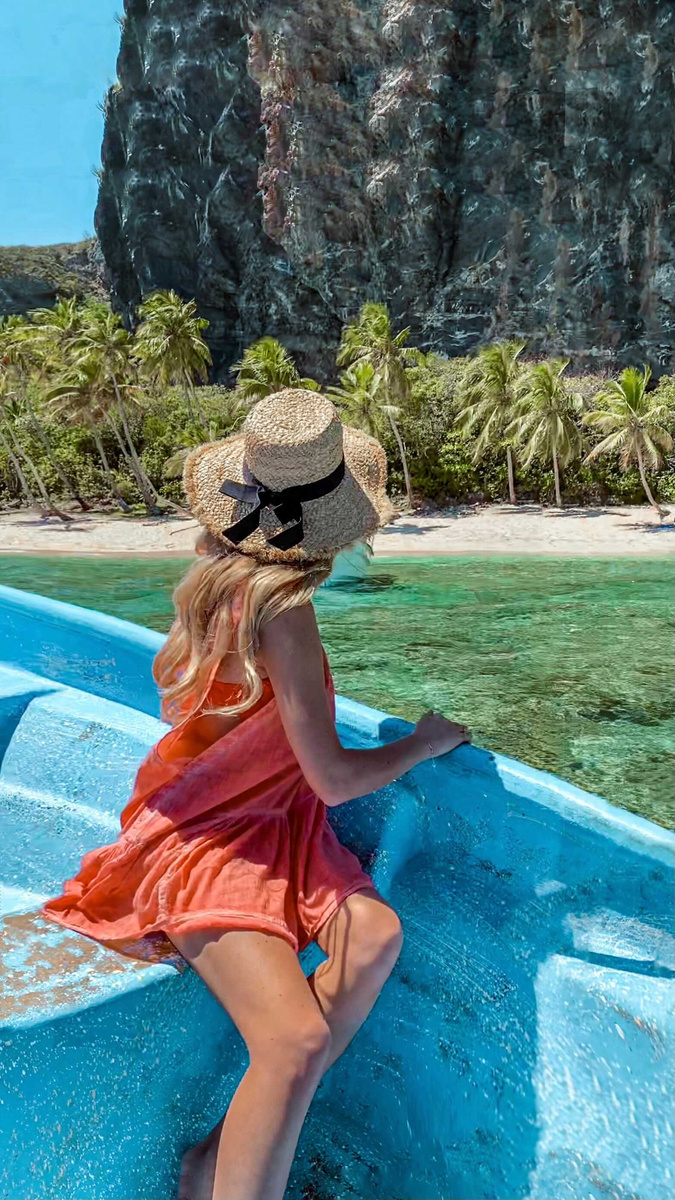 Olga travelling by boat towards the palm-covered cliffs of Playa Frontón.