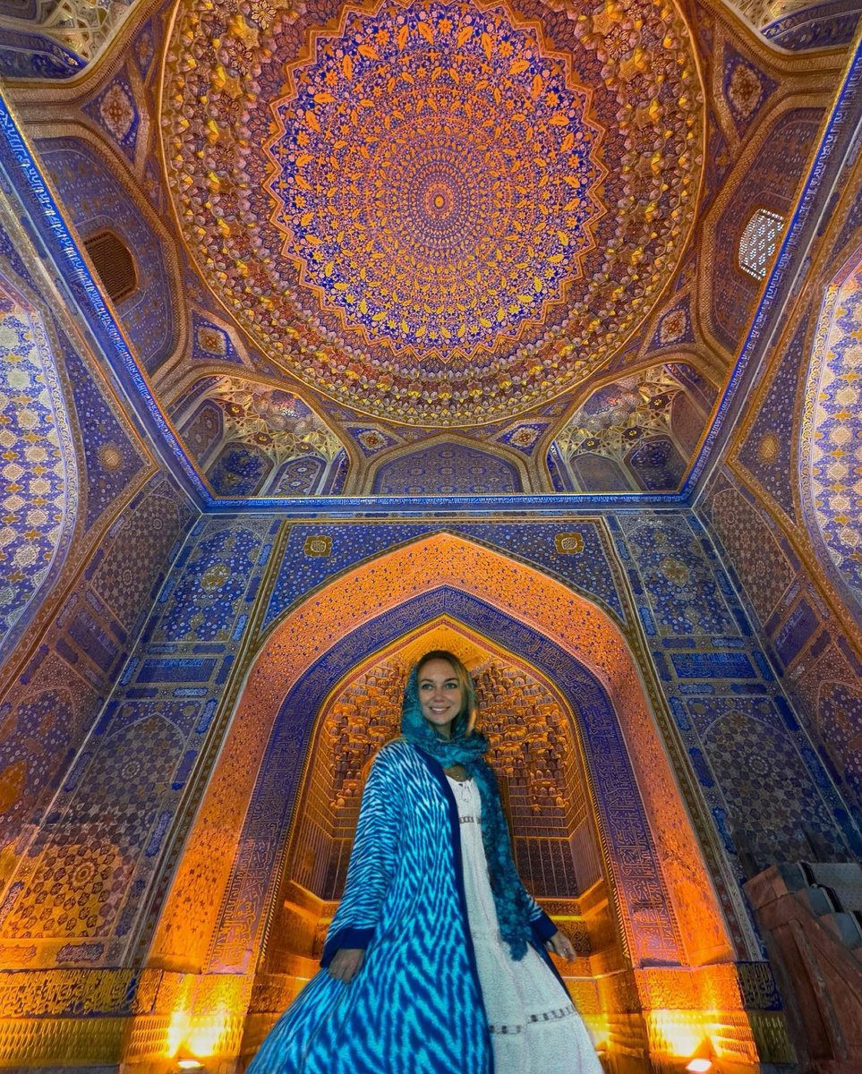 Olga beneath an ornate blue and gold domed ceiling in Uzbekistan.