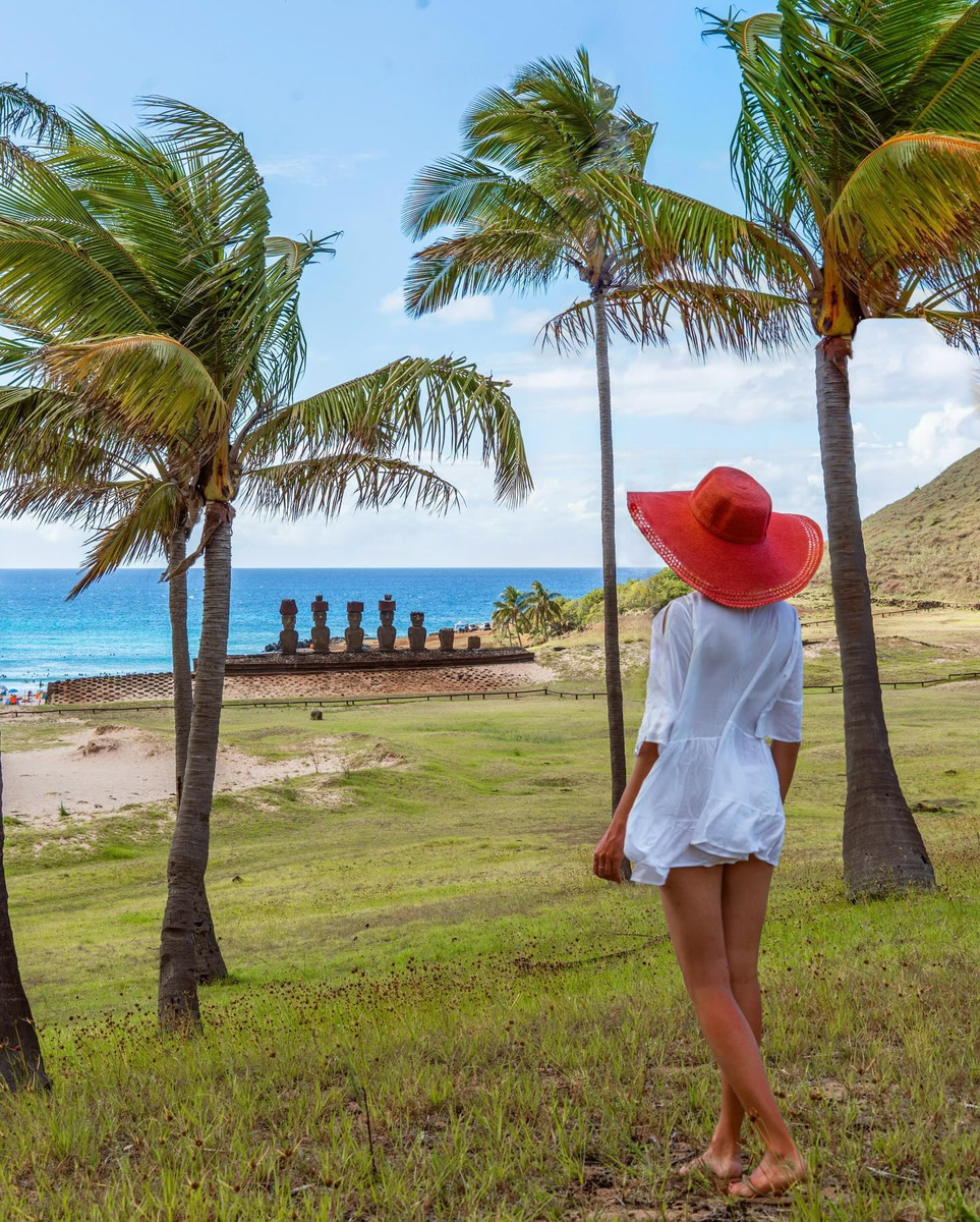 Olga looking across a palm-lined shore towards the moai of Ahu Nau-Nau on Easter Island.