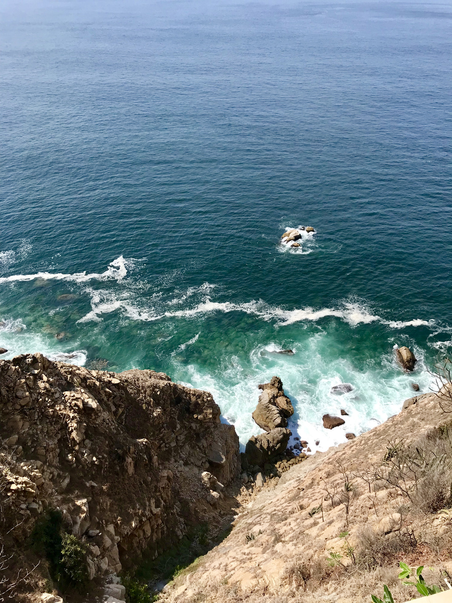 Turquoise Pacific water breaks against the steep rocky coast below Banyan Tree Cabo Marqués.