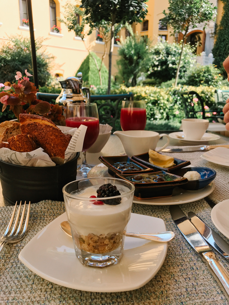 Yoghurt, sesame bread, preserves, cheese and tomato juice on a breakfast table in the Four Seasons Sultanahmet courtyard.