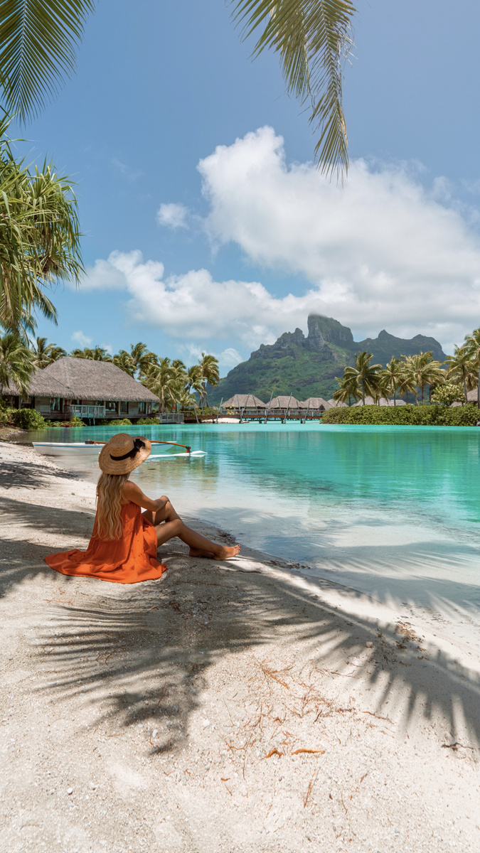 Olga sitting on white sand beside the turquoise lagoon at Four Seasons Bora Bora
