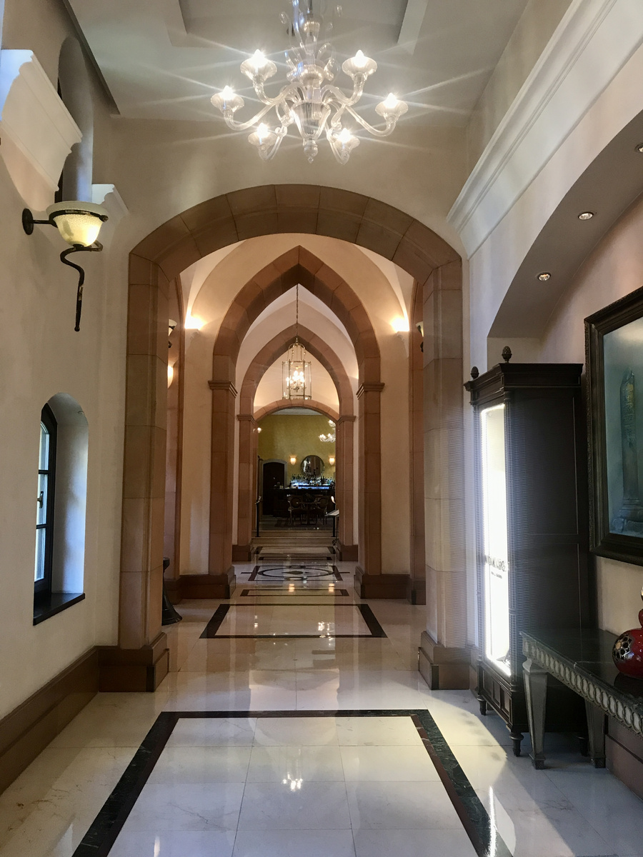 A long interior corridor at Four Seasons Sultanahmet passes beneath repeated pointed arches and glass chandeliers.