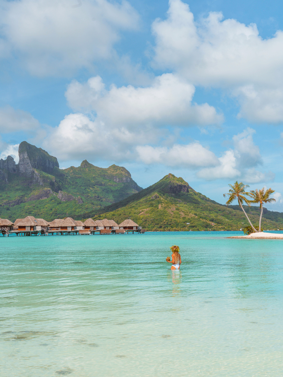 Olga standing in clear shallow water with overwater bungalows behind her at Four Seasons Bora Bora