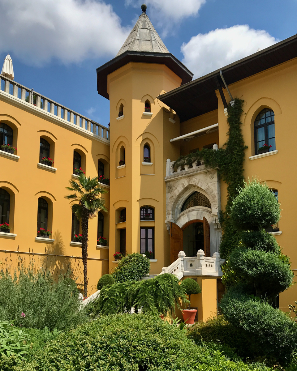 The ochre former-prison wing of Four Seasons Sultanahmet, with a corner tower, arched windows and garden planting.