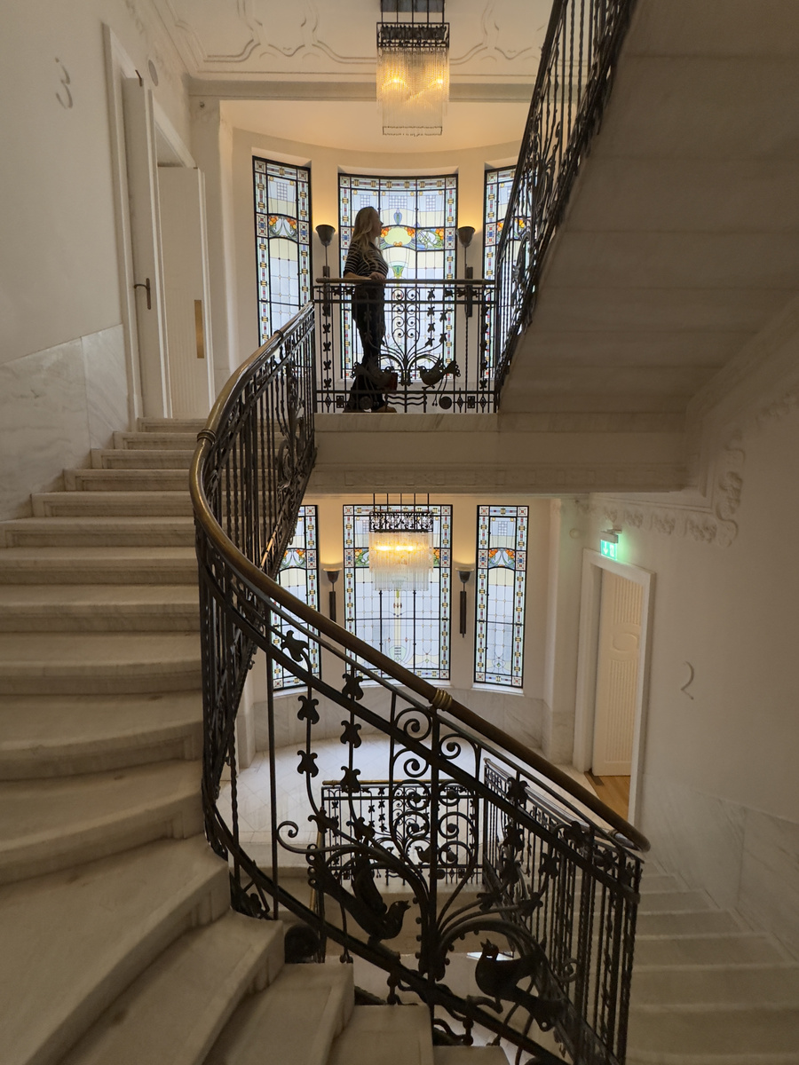 A sweeping marble staircase with dark wrought-iron balustrades curls through Four Seasons Gresham Palace.