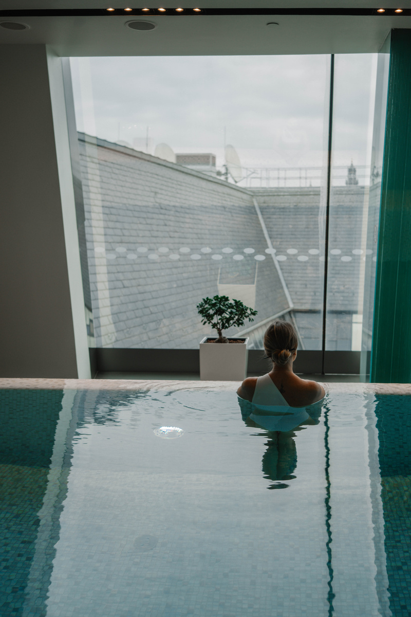 Olga stands in the indoor pool facing its glass wall and the Budapest rooftops beyond.