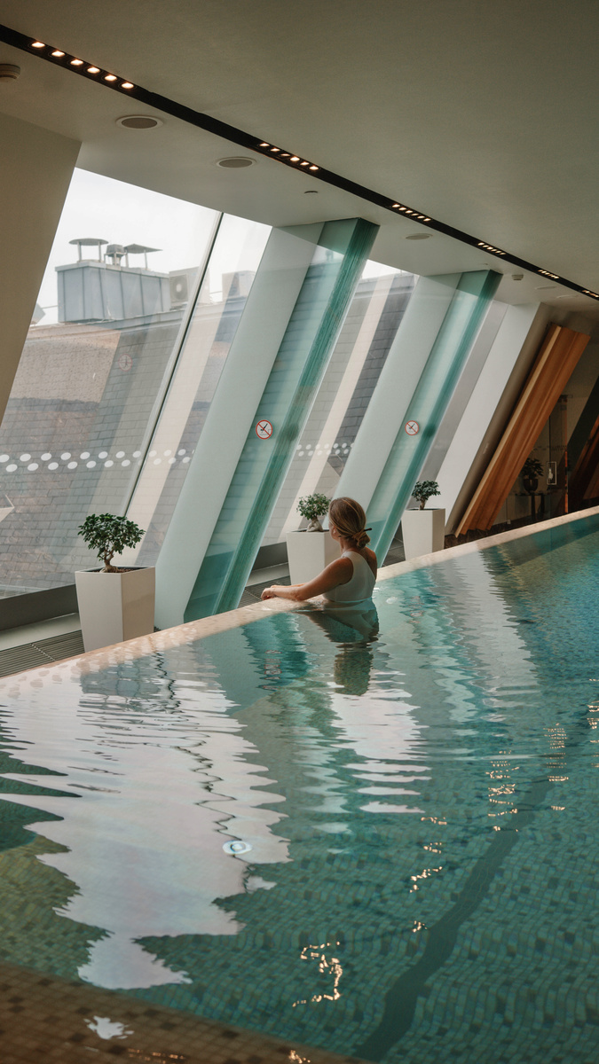 Olga pauses in the indoor pool at Four Seasons Gresham Palace beside its sloping glass windows.