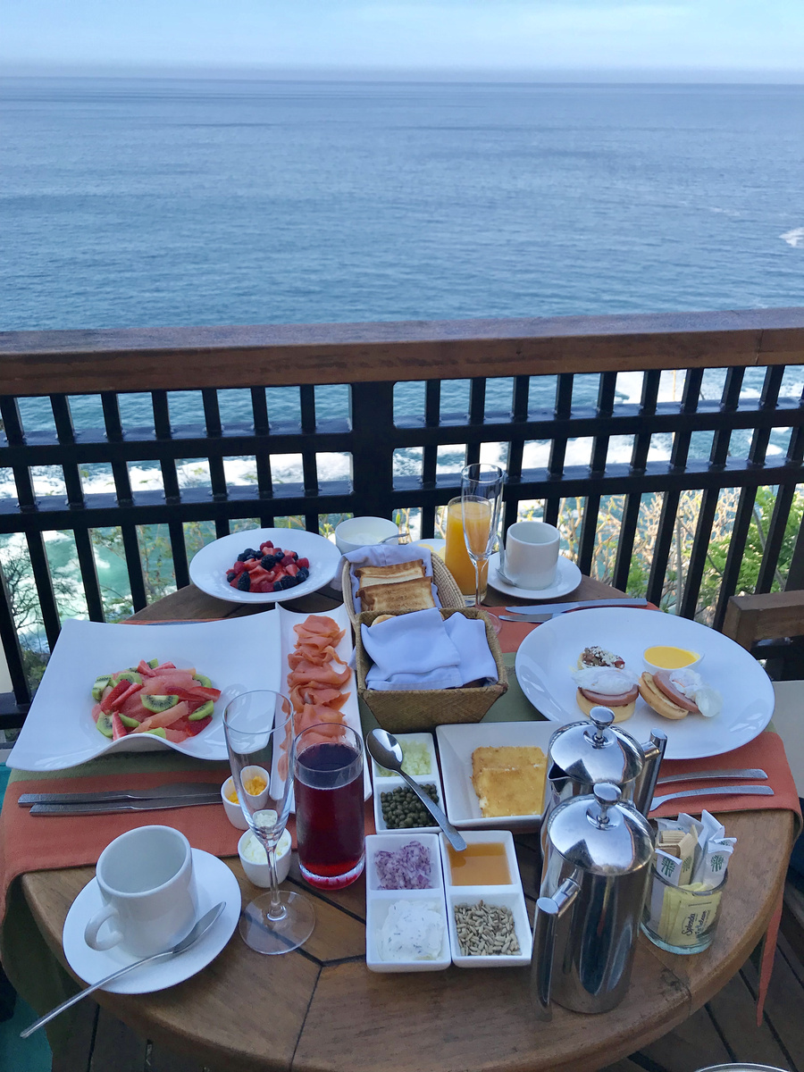 Coffee, fruit, eggs, toast and juice are set on a terrace table above the Pacific.