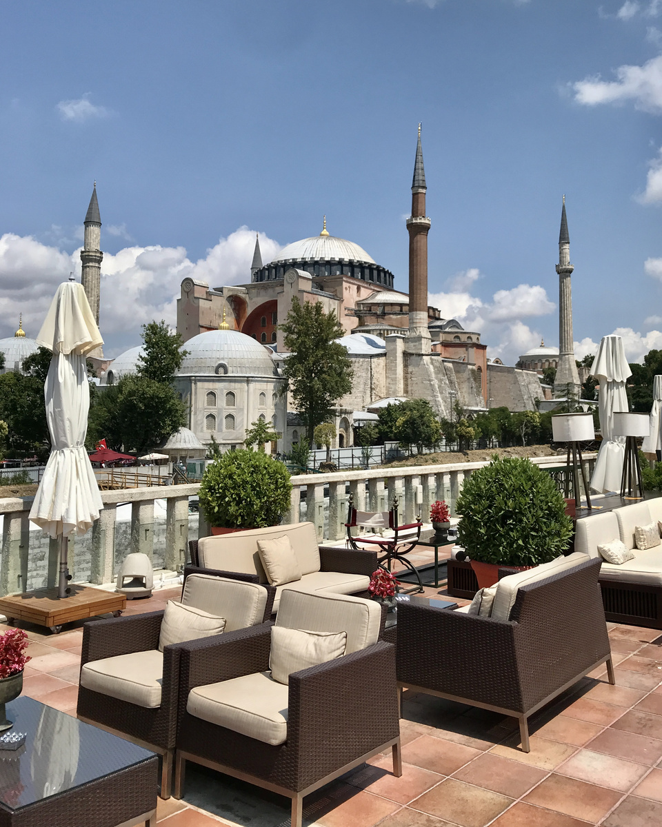 Hagia Sophia fills the view beyond chairs, umbrellas and potted shrubs on the Four Seasons Sultanahmet roof terrace.