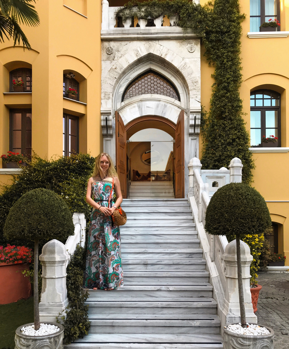 Olga stands on the marble steps at the arched courtyard entrance of Four Seasons Sultanahmet.