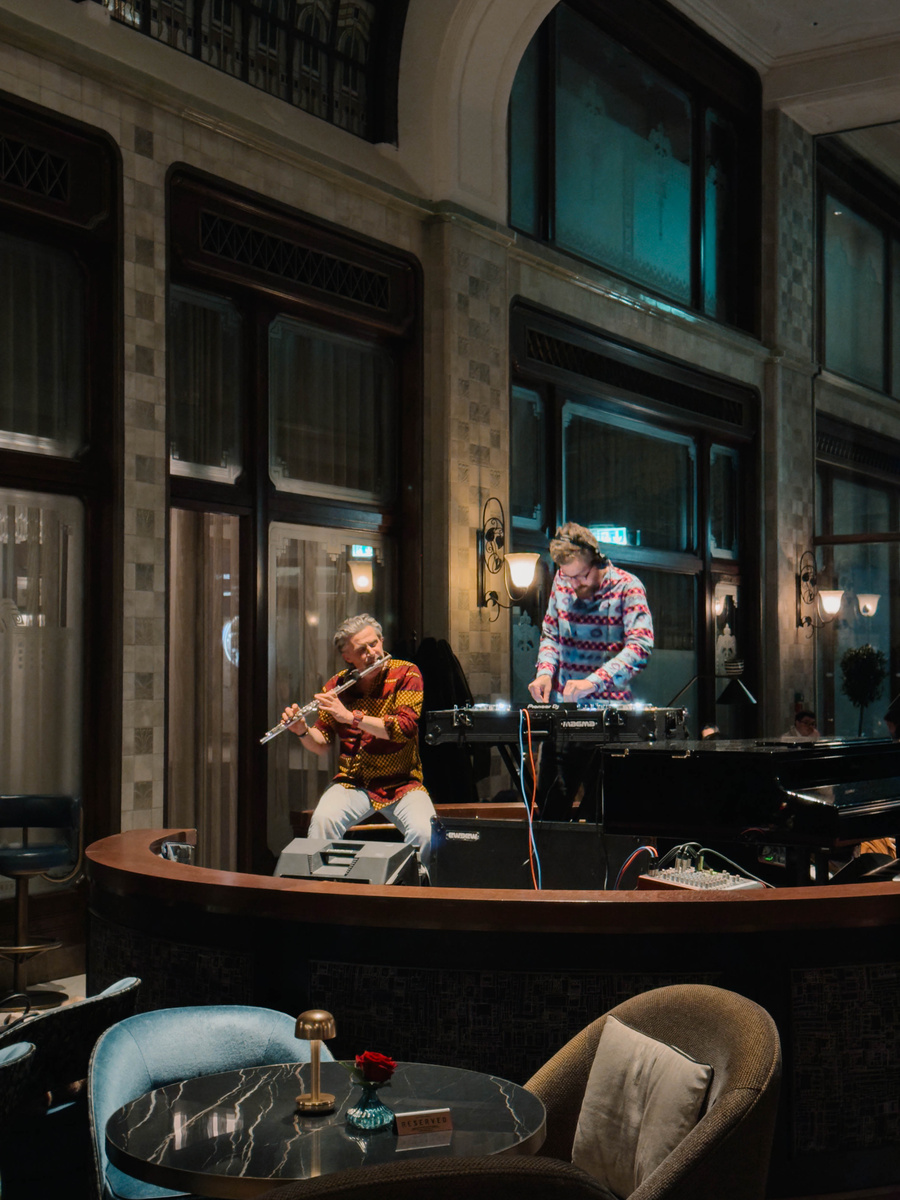A flautist and electronic musician perform beside a grand piano at MÚZSA in Gresham Palace.