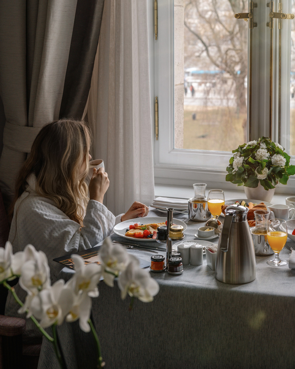 Olga sits beside the breakfast table and looks through the guest-room window over Budapest.