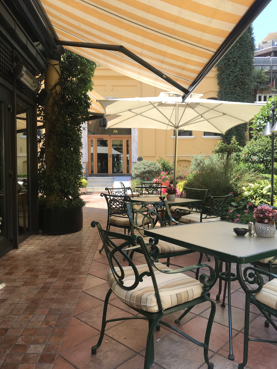 Wrought-iron tables, striped awnings and flowering plants fill the enclosed courtyard at Four Seasons Sultanahmet.