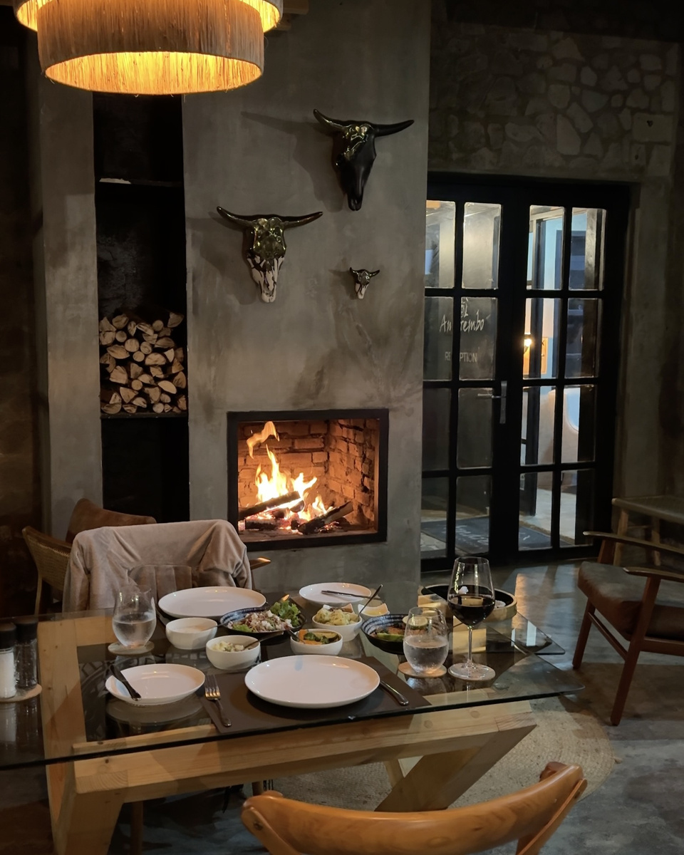 A breakfast table is set with coffee, juice and dishes beside the Amarembo fireplace.