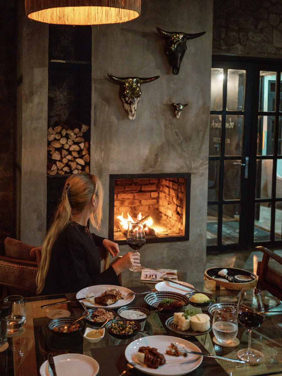 Olga sits at a dinner table beside a bright fireplace in Amarembo’s dining room.