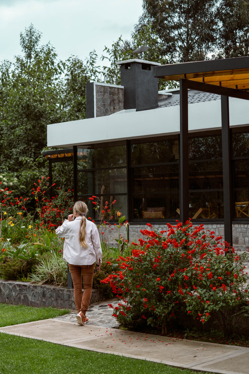 Olga walks through red flowers beside Amarembo’s glass-walled main building.