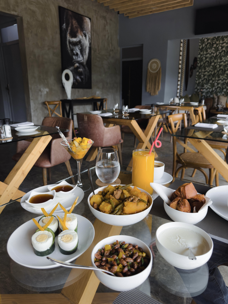 Chicken curry, beef, yam, couscous, corn salad and eggs are arranged across a dining table at Amarembo.