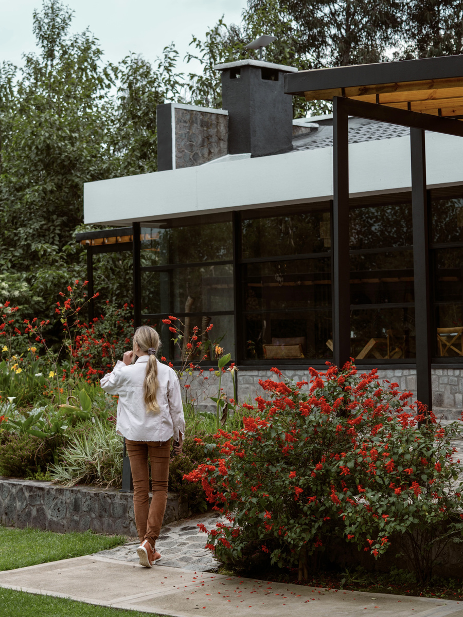 Olga walks beside red flowers and the clean-lined glass facade of Amarembo’s main lodge.