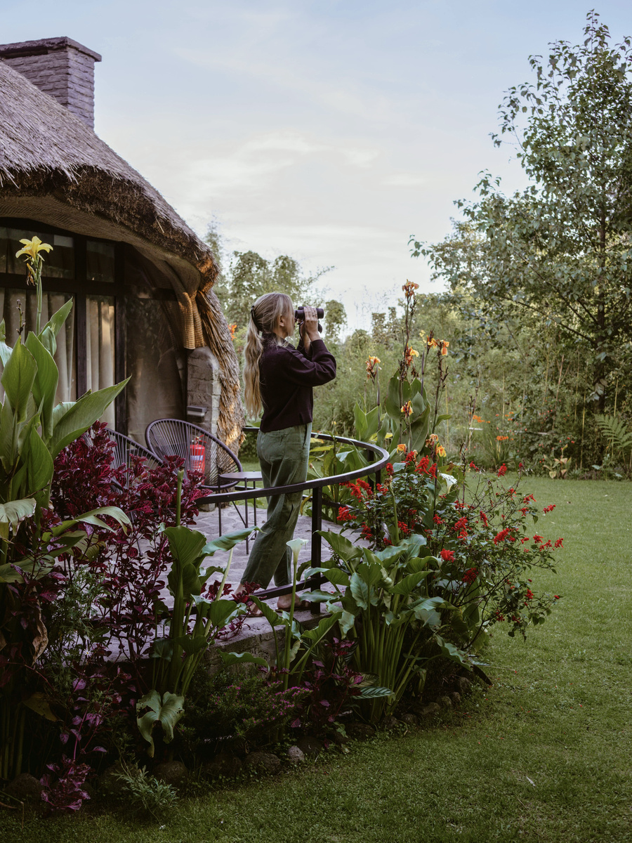 Olga pauses beside tall red flowers in Amarembo’s landscaped garden.