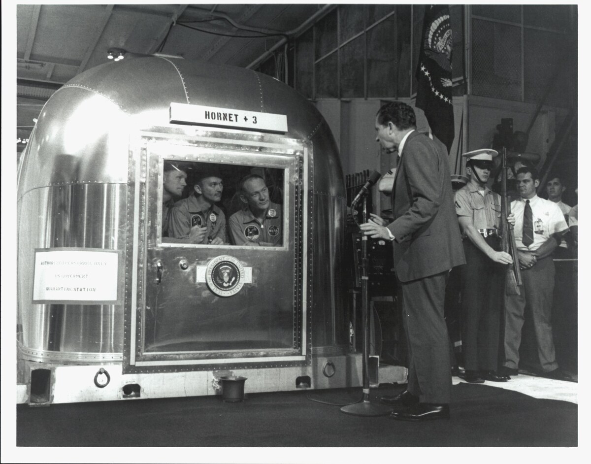 President Richard Nixon speaks to Neil Armstrong, Michael Collins and Buzz Aldrin through the window of the Apollo 11 Mobile Quarantine Facility.